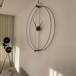 Minimalist oversized wall clock with thin metal rings and wooden center mounted on a white living room wall.