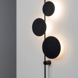 Vertical wall lamp with three black circular panels and backlighting.