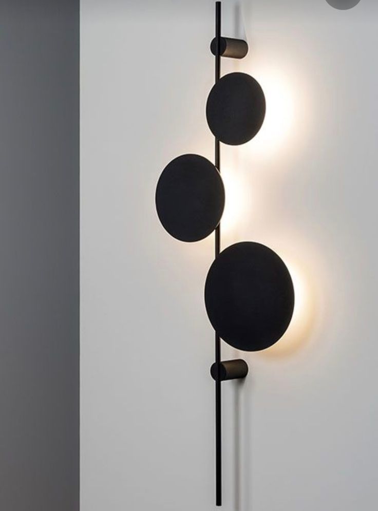 Modern Vertical Disc Wall light Vertical wall lamp with three black circular panels and backlighting.
