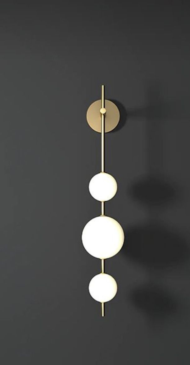 Minimalist Triple Globe Vertical Light Sleek vertical wall light with three glowing spheres on a brass rod.