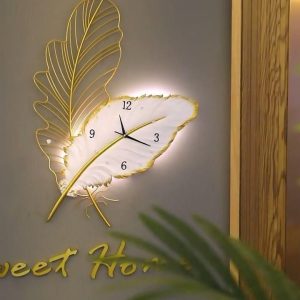 A luxurious gold and white wall clock shaped like a leaf with built-in LED backlighting.